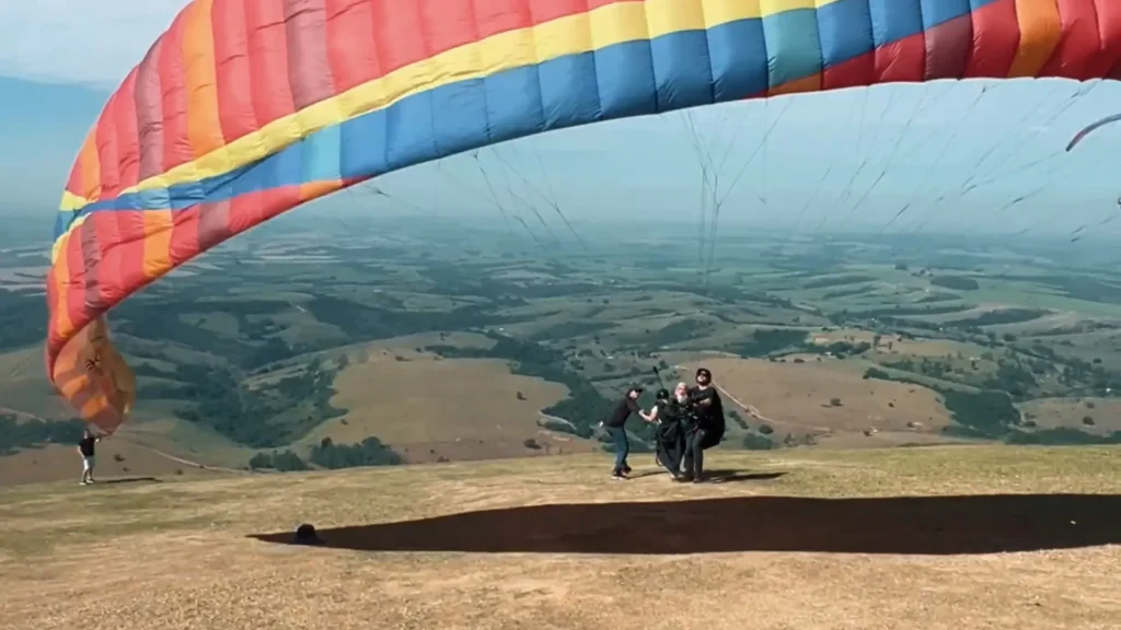 Águas de São Pedro: Um Destino Imperdível no Interior Paulista para Natureza, Relaxamento e Aventura 7 Instrutor Branco com equipamento de parapente explicando voo