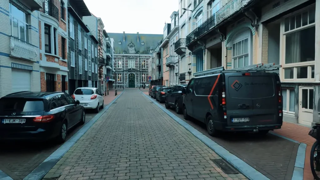 Rua estreita e pavimentada em Blankenberge com edifícios históricos nas laterais e um prédio ornamentado ao fundo