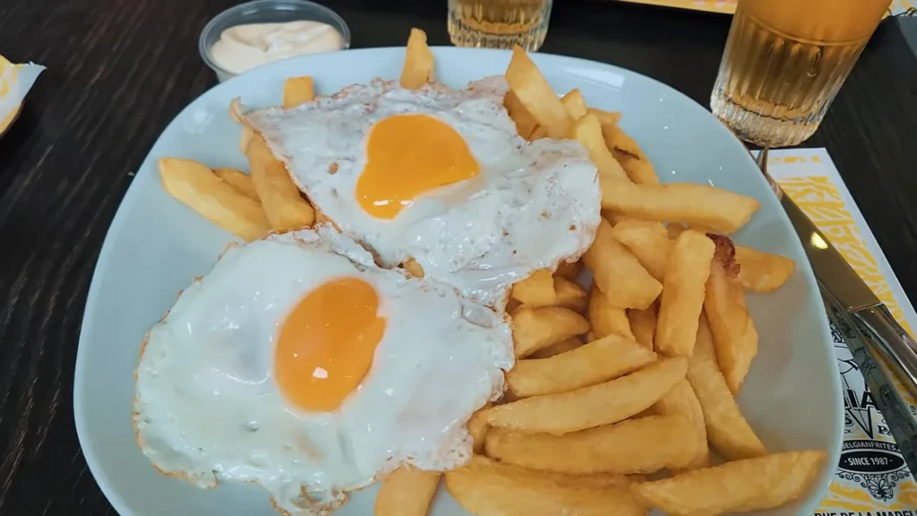 Prato de batatas fritas belgas com dois ovos fritos por cima