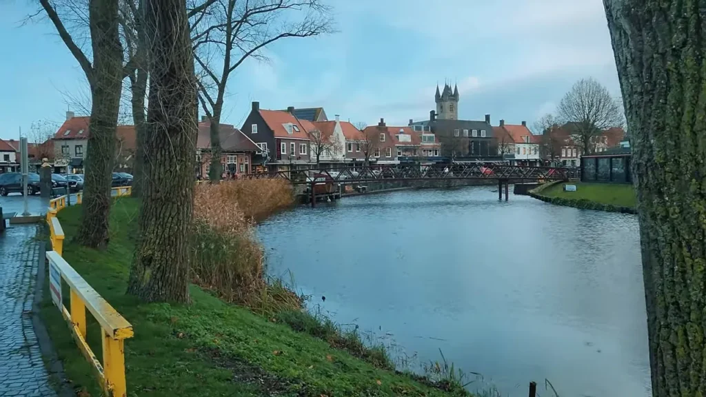 Canal com ponte, casas típicas e torre da cidade ao fundo, vista panorâmica