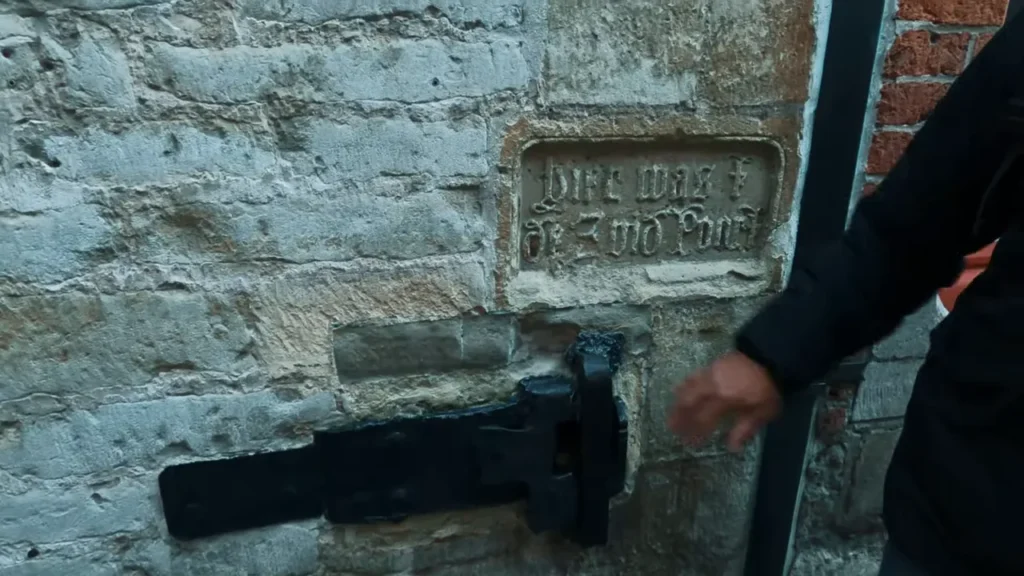 Inscrição medieval na parede ao lado de trava de ferro do portão