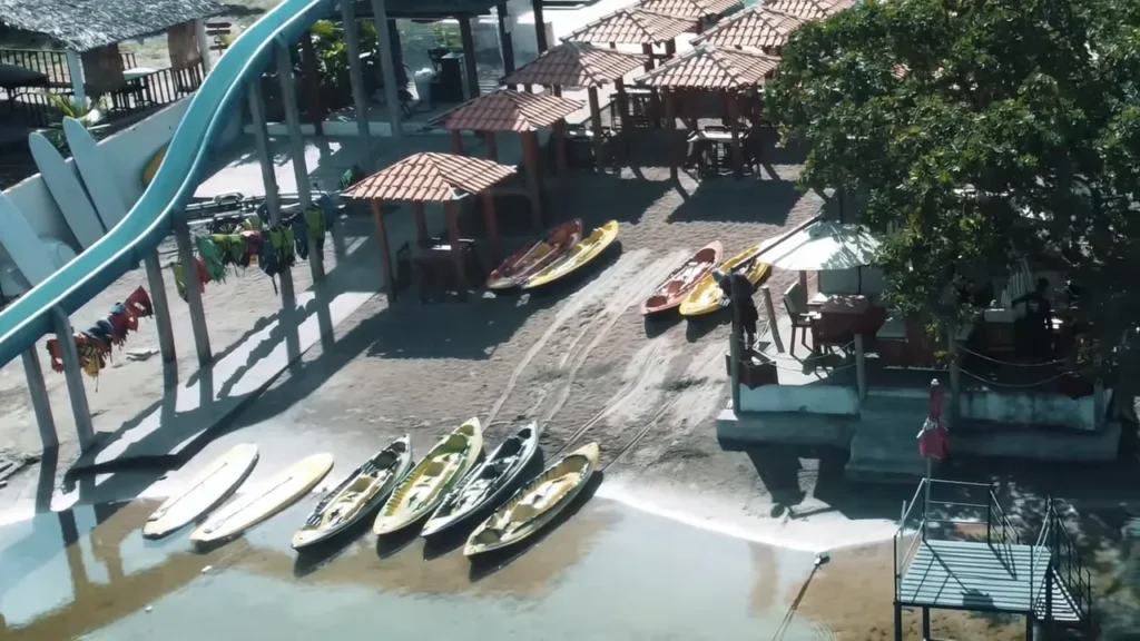 vista aérea/obliqua de caiaques e barracas na margem com trilhas de pneus na areia