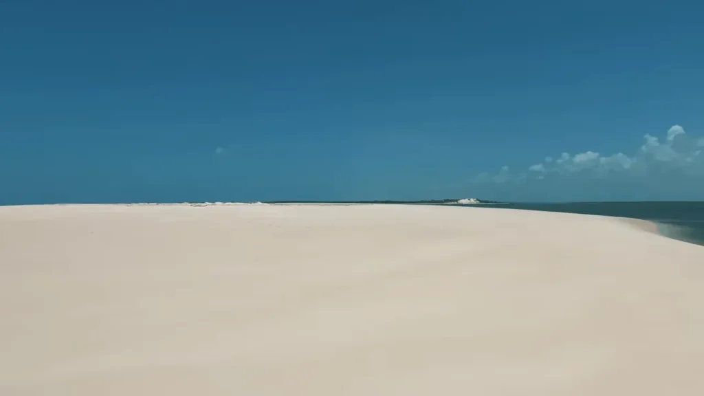 Duna e banco de areia curvado com trecho de mar e ilhota ao longe