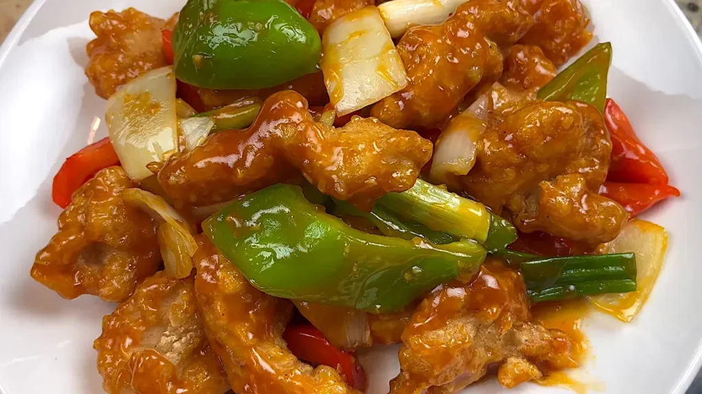 Frango agridoce crocante com legumes coloridos e molho brilhante no prato
