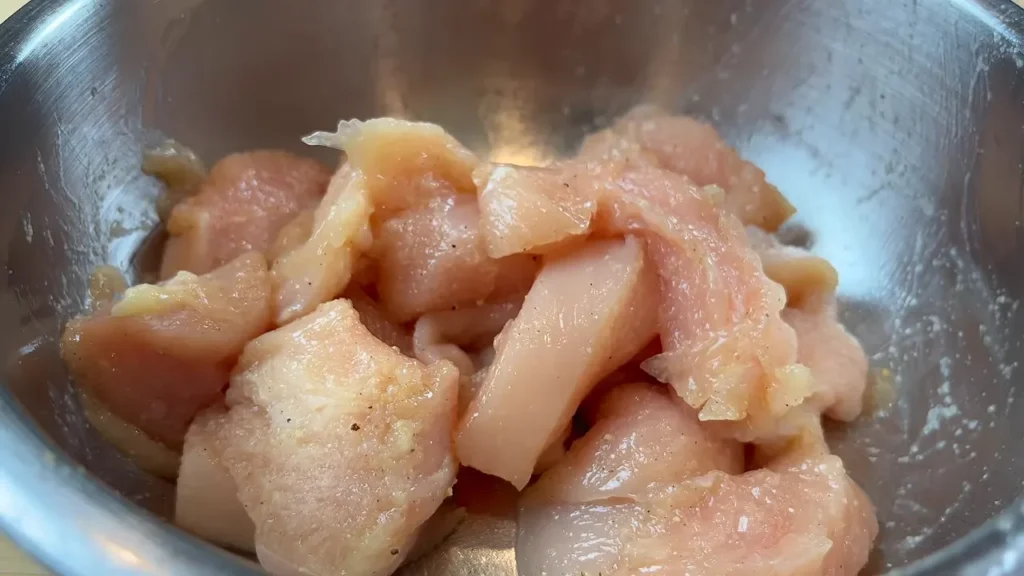 Frango em pedaços no recipiente para marinada do frango agridoce
