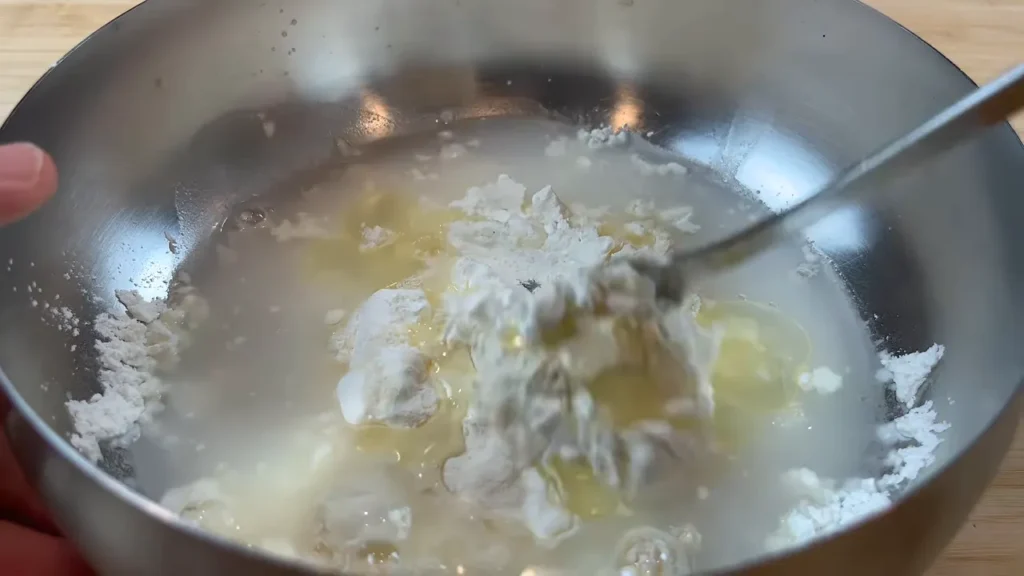Água sendo adicionada à massa de fritura de frango agridoce para formar uma mistura lisa