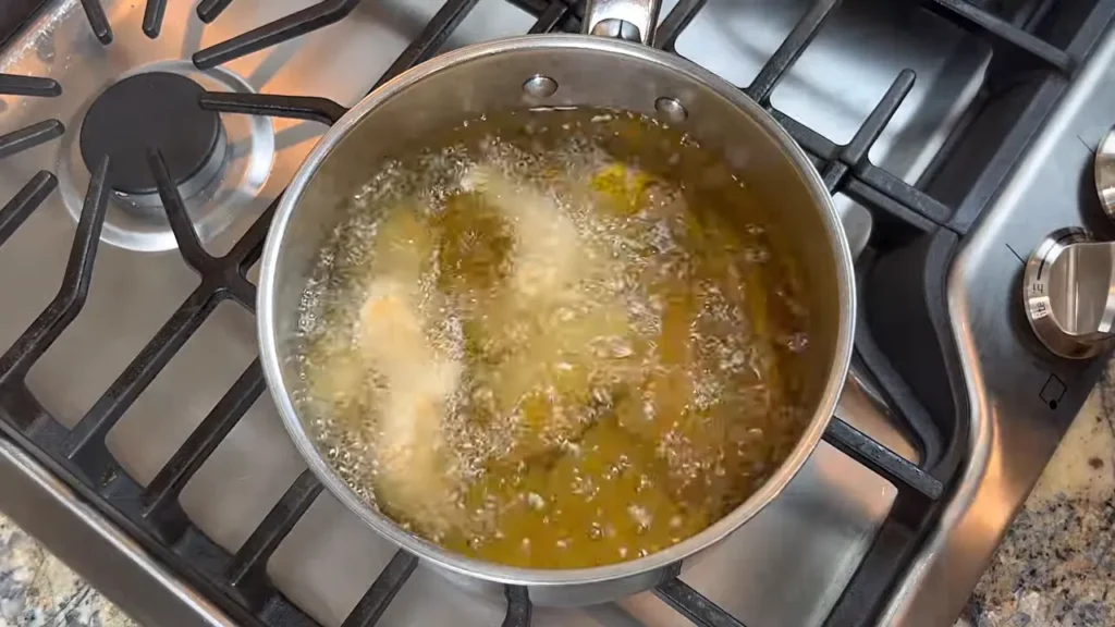 Frango agridoce fritando por 30 segundos em óleo quente para deixar a casquinha crocante