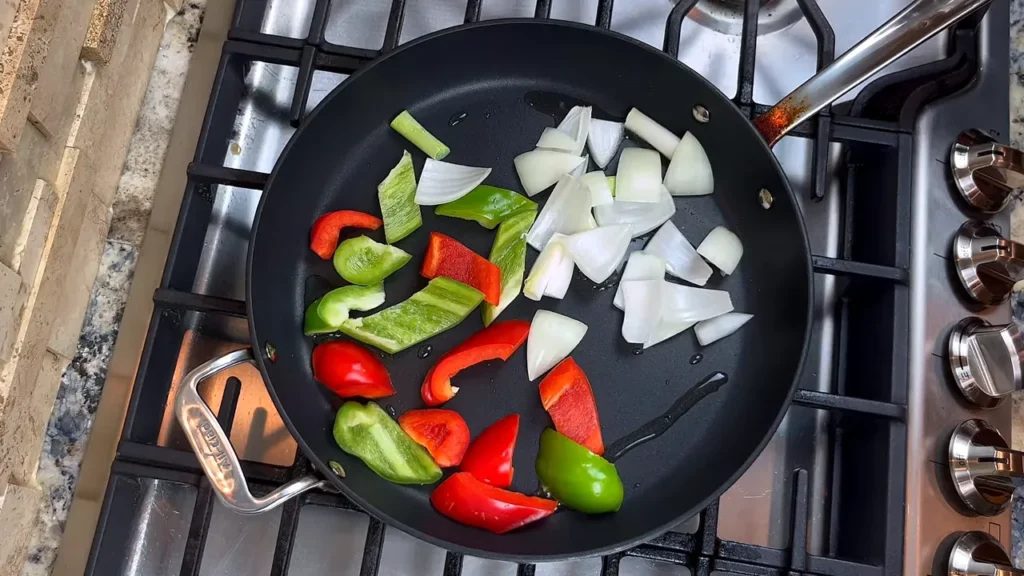 Frigideira com cebola, pimentão e cebolinha cortados para saltear no frango agridoce