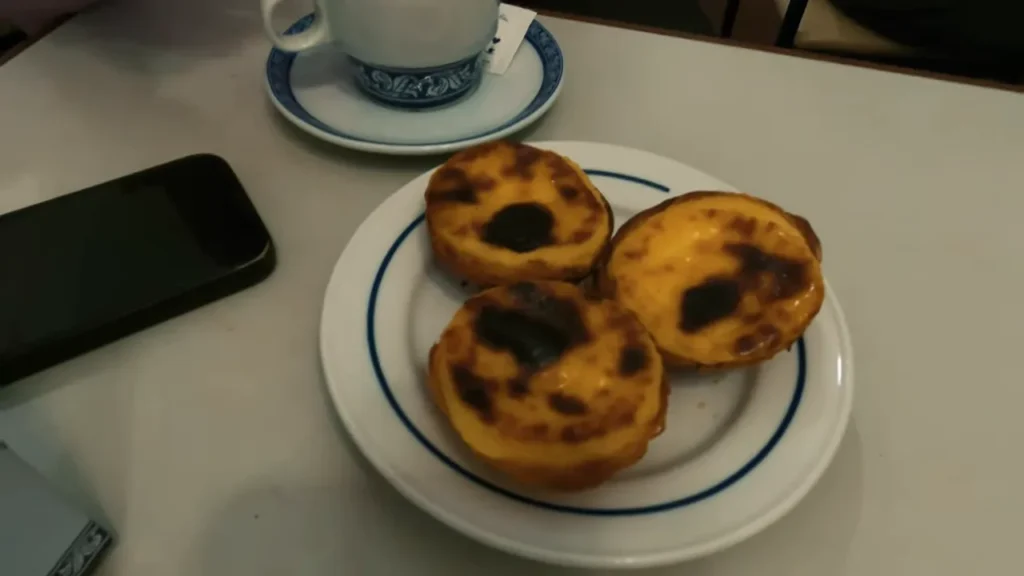 Lisboa: Roteiro Completo de Um Dia em Belém, Centro e Parque das Nações 17 Casal compartilhando pastel de nata em mesa externa enquanto finaliza o dia em Lisboa